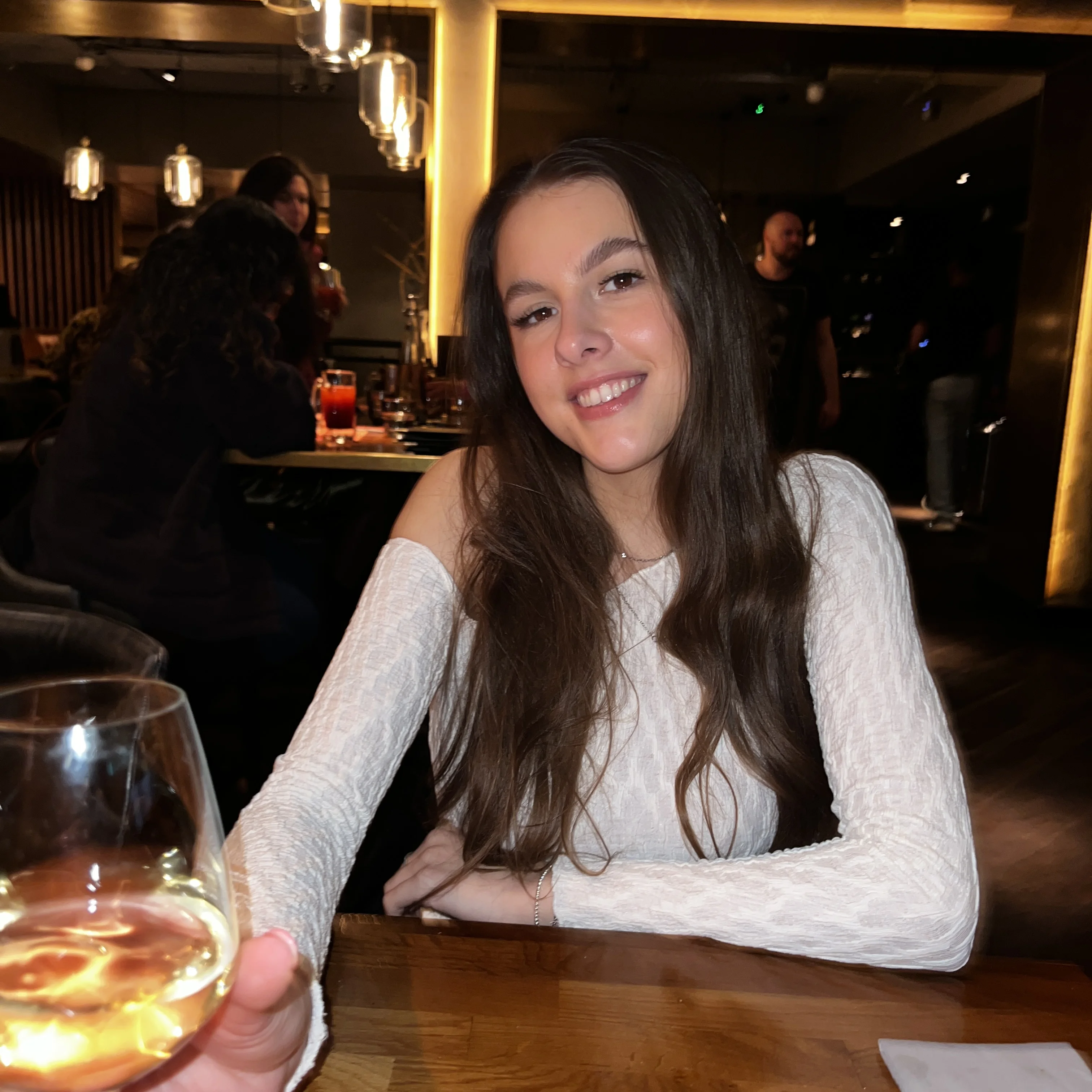 A friend sitting across the table drinking a cocktail